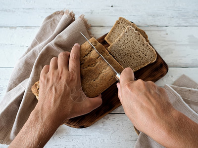 乡村女手切面包位于木质表近纸巾白木背景最佳观点烘烤概念乳房农业美食图片