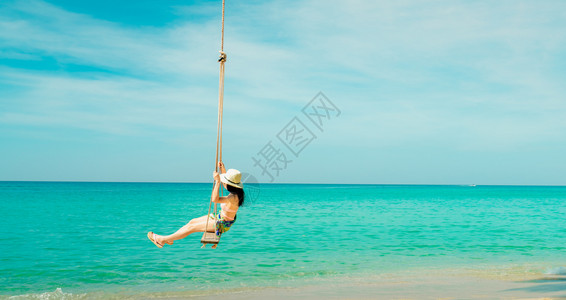 女士自由穿着粉红泳衣和草帽的快乐亚洲年轻女在热带天堂海滩享受节假日绿色海水蓝天空和云彩的暑假时装女孩在摇摆中的欢乐比基尼背景图片