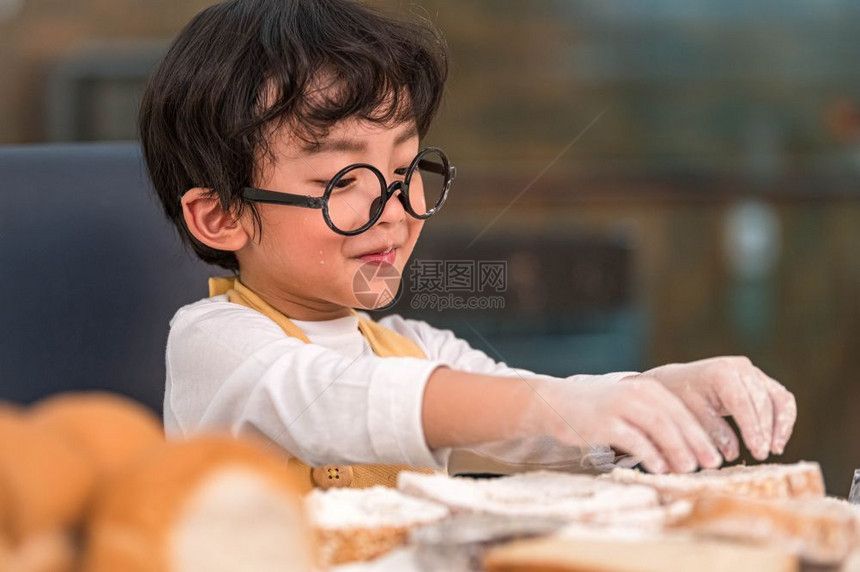 制服亚洲人喜欢烘烤面包的亚洲小快乐男孩在家厨房里很滑稽人们的生活方式和家庭自制食物原料概念烤圣诞蛋糕和饼干人们的生活方式和家庭自图片