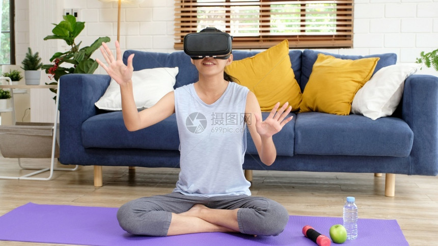 在家运动电子体育在家里运动快乐的亚洲女孩在健身时玩越快康的妇女身着虚拟现实头耳机和身体力交互解剖家庭客厅中的女和穿戴技术人的健康图片