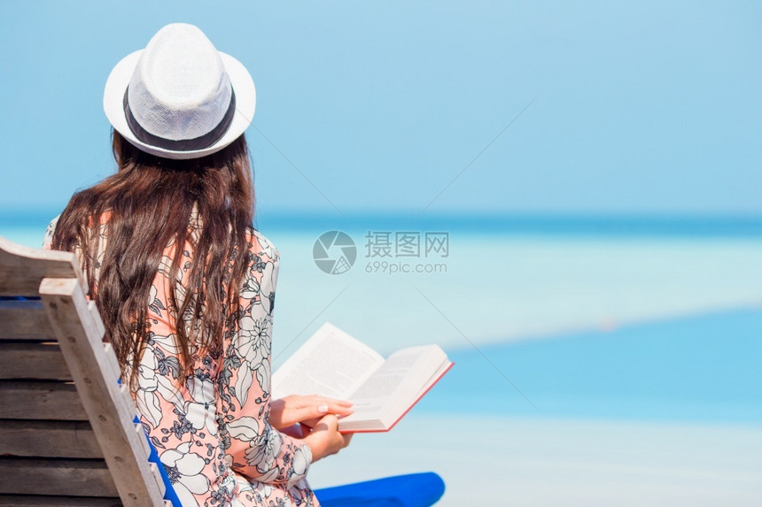 天堂女士一位在海滩上轻松放的年女子肖像她读了一本书在热带白色海滩期间一名年轻女子在海滩上休闲阅读一本书夏天图片