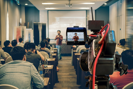 电影创业素材男人在商业或教育研讨会活动和概念的议室放映屏幕上在展示式屏幕上播放亚洲演讲人随身穿便装在舞台上拍摄的闭场录像片段制套装人们背景