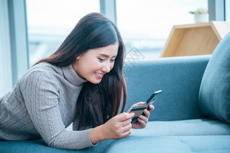 在线的购买技术亚裔女使用智能手机阅读网络社交媒体购物网站在Smartphone上微笑脸的智能手机网站上使用智能手机阅读线上社交媒背景图片
