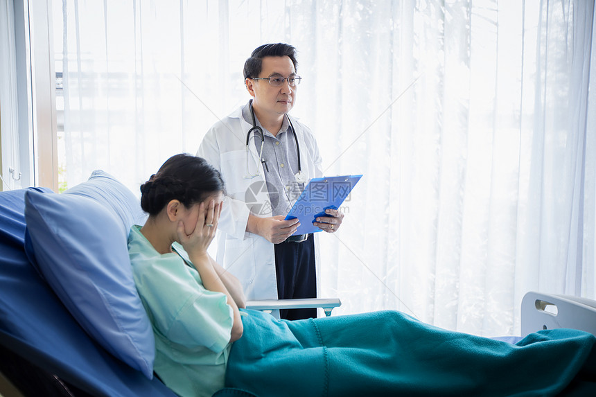 护士健康诊断医生向躺在院床上的一位女病人询问和解释情该名女人在医院卧床图片