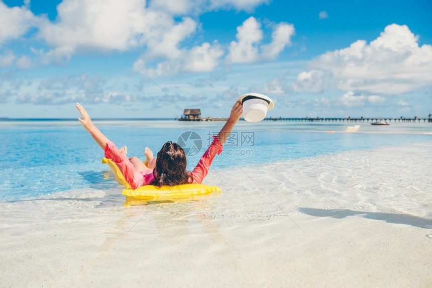 年轻的人们女士在无限游泳池里有空气床垫在游泳池里放松的年轻快乐女人背部图片