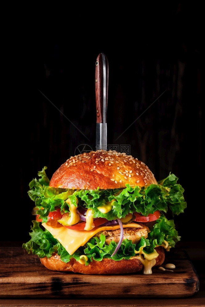 自制洋葱不良土烤汉堡包配有火鸡切菜奶酪酱和木板上的蔬菜在黑暗背景上贴近有选择地聚焦于复制空间垂直框架图片