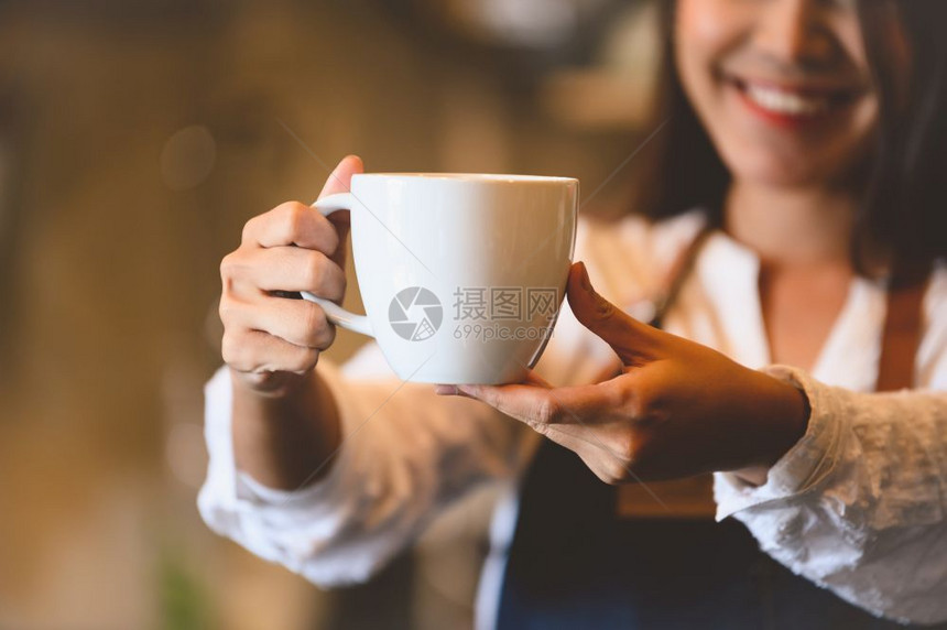 工人关闭白咖啡杯为客户提供有美丽的亚洲女律师协会背景的白咖啡杯供职和业服务食品和饮料咖啡店及和餐馆拥有权单位美元女服务员图片
