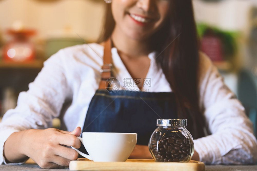 职员女士关闭白咖啡杯为客户提供有美丽的亚洲女律师协会背景的白咖啡杯供职和业服务食品和饮料咖啡店及和餐馆拥有权单位美元咖啡师图片