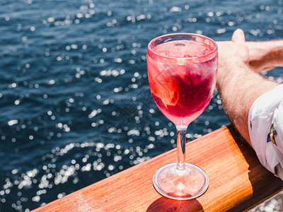 西班牙甲板栏杆朗姆酒美丽的杯有粉红鸡尾酒和冰块在海浪的背景下站在露天的甲板上侧观近距离的休闲概念带着粉红鸡尾酒和冰块旅行新鲜的背景
