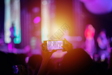 留音机观众举手使用智能机在明亮的舞台灯下拍照和录像校对Portnoyunorg俱乐部鼓掌音背景