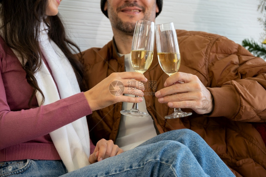 保持坐在沙发上客厅的圣诞新年和爱情概念中喝着香槟杯的浪漫情侣快乐夹克图片