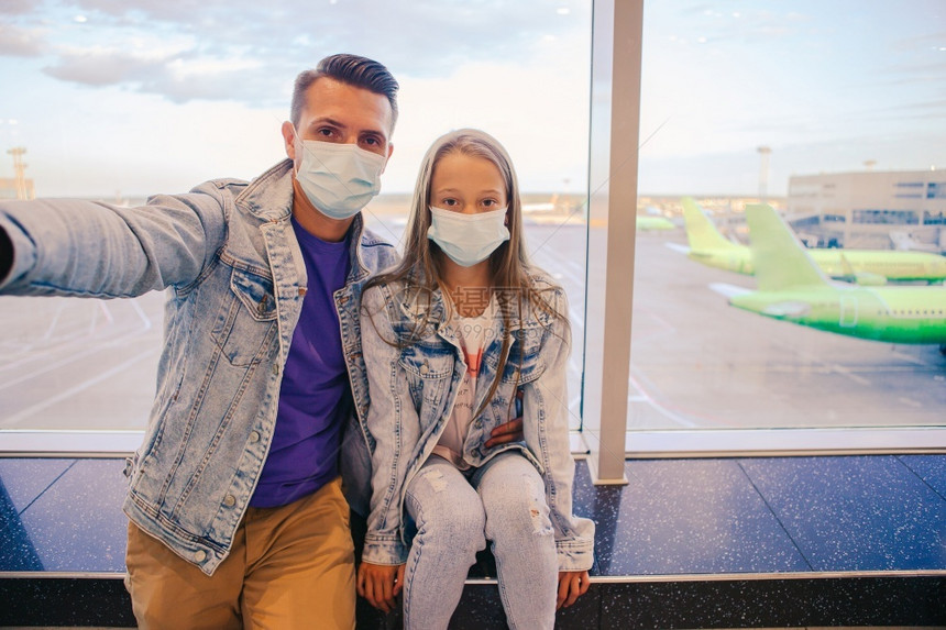 父亲和儿童在科罗纳和流感爆发期间戴面罩保护他们免受科罗纳的侵袭在机场防科罗纳和抓抱带医疗面具的爸和小女孩身上戴头罩防止科罗纳和抓图片