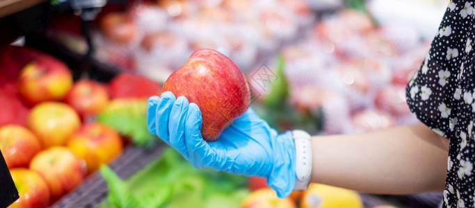 拐点食物购中心妇女在超市或杂货店内戴硝化手套和持有红苹果子保护阴冠渗透卫生新正常和19大流行后的生活背景