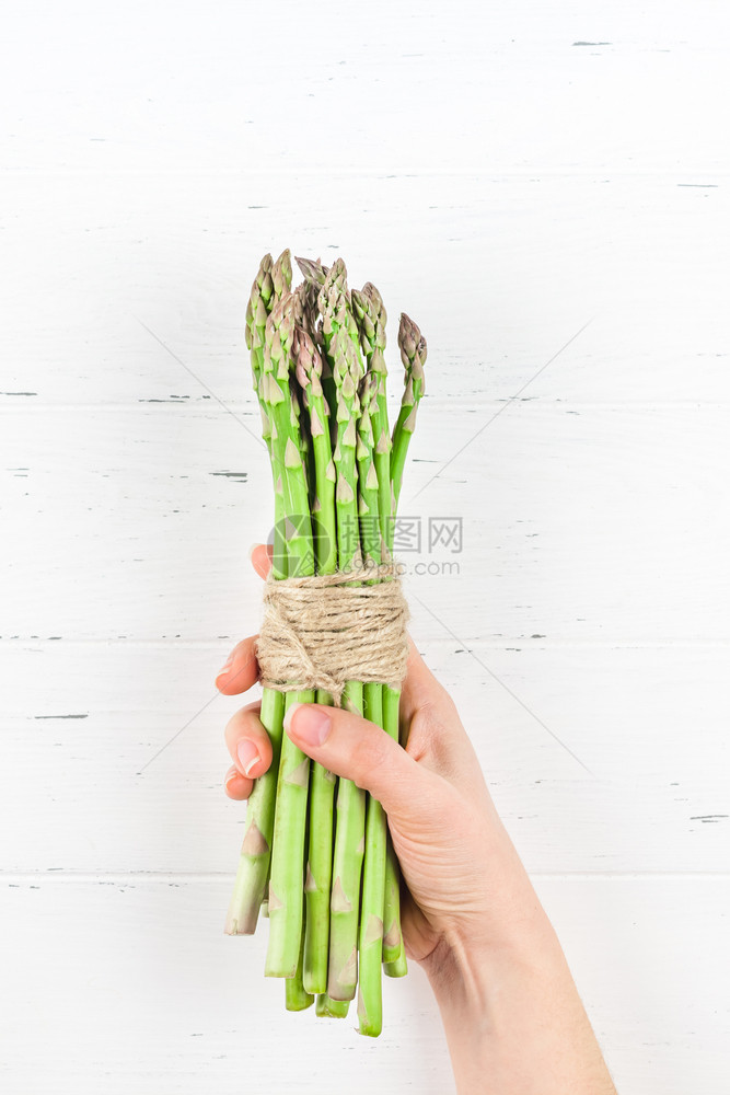 美味的女在白色木制桌背景上将最小房屋烹饪概念复制到博客或食谱书中最顶尖的画面显示女手中新鲜绿色的青香草sparagus维生素斯堪图片