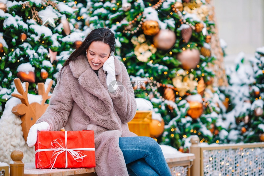 分支季节幸福Beautidul女孩圣诞节有红礼物与智能手机在雪户外的屋欢乐女孩图片