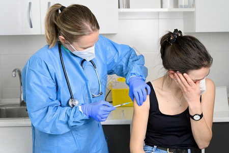 发烧预防接种疫苗戴面罩的年轻女害怕冠状疫苗不让医生在诊所注射女害怕covid19疫苗接种对全球概念进行免疫高质量照片戴面罩的年轻背景