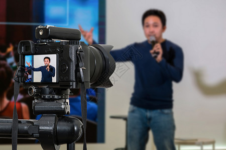技无虚发亚洲人记录舞台研讨会亚洲发言人的三脚录音视频博客摄影师相机或录像和技术现场流概念上装有麦克风的专业数字无镜照相机摄像头或录相和技背景