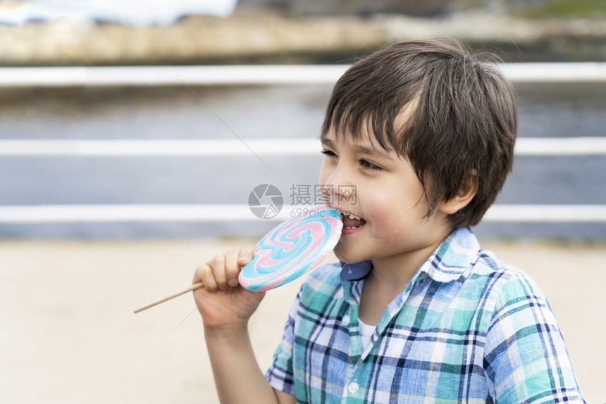 年轻的关心有趣小孩吃棒糖快乐的小男孩拿着大糖果孩子笑脸的吃甜食活跃的童年在阳光明媚的夏日享受户外游乐公主图片