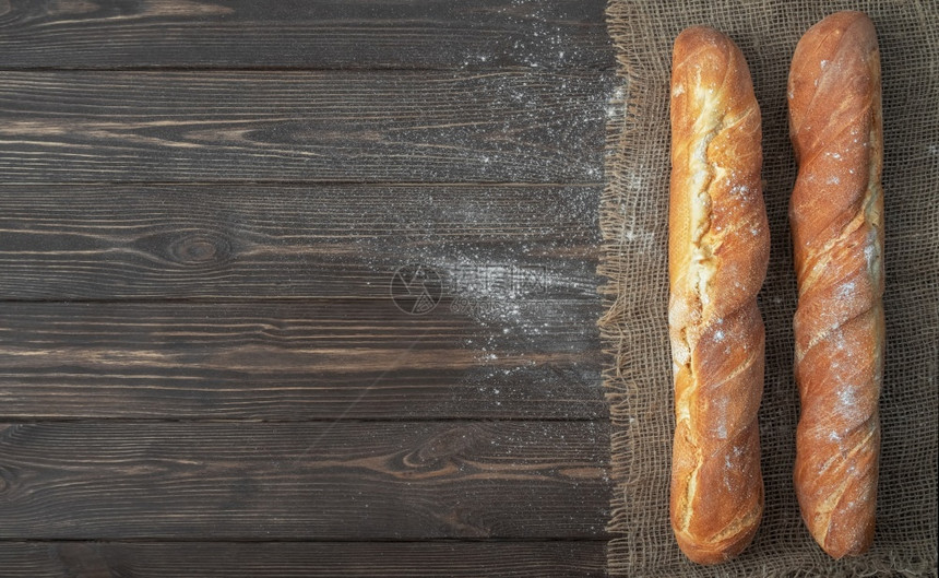 美味的白色面粉冷烘烤包后用白粉制成的法国新鲜袋式面包条位于勃兰布上生锈的深黑木背景小麦香脆的图片