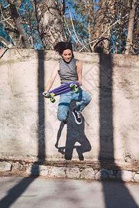 一名少年滑板运动员用便滑冰玩奥利戏法穿着随意戴自由概念木板溜冰者服装图片
