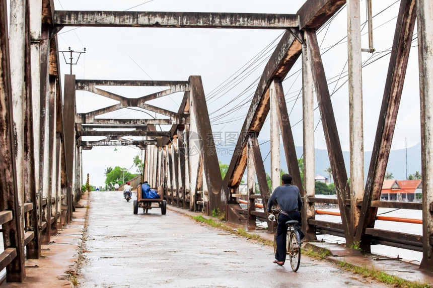 雨亚洲人高棉骑自行车和摩托穿越古老桥从法国殖民时期开始在南柬埔寨贡布建造了古老桥具有突出重点的独角桥河图片