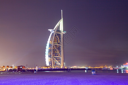 塔麦地那城市景观在阿拉伯联合酋长国迪拜Jumeirah公共海滩上晚见识到七星豪华旅店BurjAlArrab头七星级酒店背景