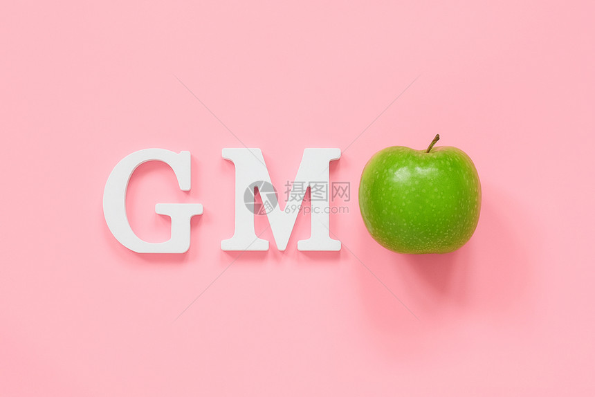治疗生态GMOtex来自白色体积字母和粉红色背景上的青苹果转基因食品或水果的概念顶视图平躺复制空间白色体积字母和绿苹果的GMO粉图片