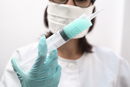 制药服医疗的一名身戴面具和手套的护士在现代诊所内携带注射疫苗的器图片
