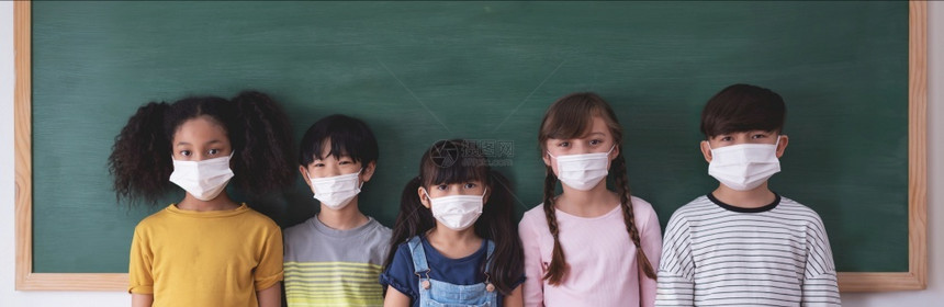 一群戴口罩的儿童站在黑板前图片