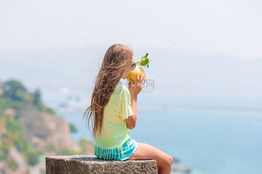 旅游的孩子意大利阿马尔菲海岸背景的小女孩在地中海和天空背景中手握着大黄柠檬在海洋和天空背景下旅行图片