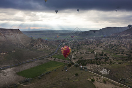 红色山梅一个五颜六色的气球在黎明时分飞越卡帕多西亚山谷的景色土耳其一个气球在卡帕多西亚的山谷上空飞行天线航班热气球背景