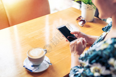 妇女手握机空白复制间屏幕文字信息内容女在咖啡店休息时通过手机在电话上读取消息的空版间屏幕文本信息内容木制的细胞卡布奇诺背景