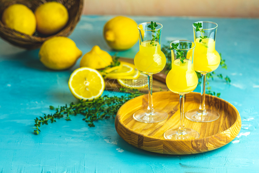 果汁林肯切罗与百草枯在三个格拉帕斯葡萄酒杯的木托盘中新鲜柠檬在篮子上浅水泥桌的淡混凝土酒吧食谱图片