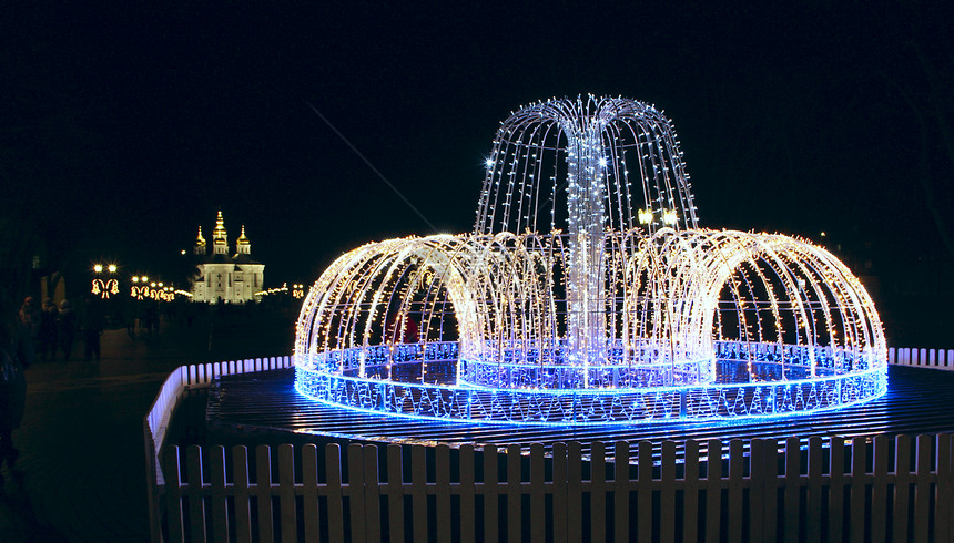 维生素镇明亮的由彩灯制成LED人造喷泉五颜六色的新年花环NewYearrsquos灯城市全景vith由花环和带有纹灯笼的大道和教图片