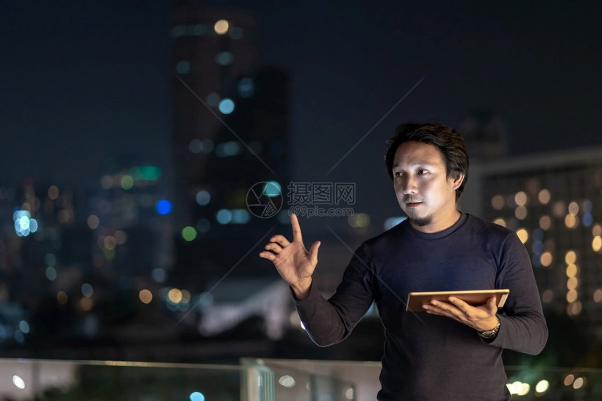 联系亚洲创意自由职业者使用技术平板机在泰国Bangkok河边金融区采取微笑行动商业技术与职概念利用技术平板机城市景观无线的图片