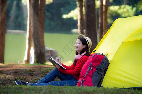 一名年轻女孩坐在露营帐篷外写作图片