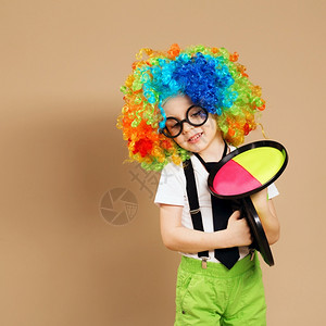 吹大号男孩穿着大号有色假发的快乐小丑男孩肖像戴着小丑假发和眼镜玩球游戏的小孩马团浮夸的生日背景