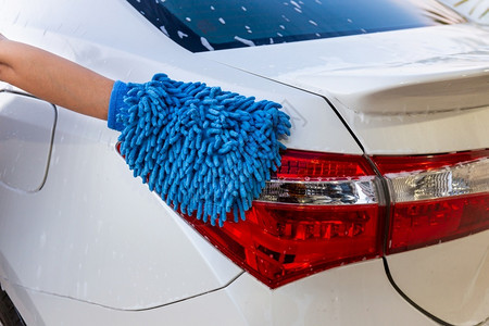 妇女手用蓝色微纤维织物洗尾灯现代汽车或清洁洗概念以及泡沫清洁器湿的图片