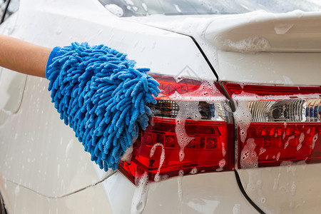 妇女手用蓝色微纤维织物洗尾灯现代汽车或清洁洗概念以及泡沫人们清洁器图片
