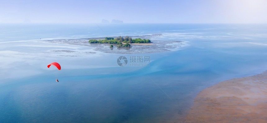 红色滑翔伞在夏季飞越蓝色海洋泰国Trang省背景的纯红树林岛上飞过蓝色海洋其空中景象模糊不清男人极端希望图片