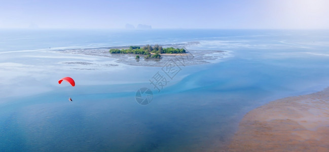 红色滑翔伞在夏季飞越蓝色海洋泰国Trang省背景的纯红树林岛上飞过蓝色海洋其空中景象模糊不清男人极端希望背景图片