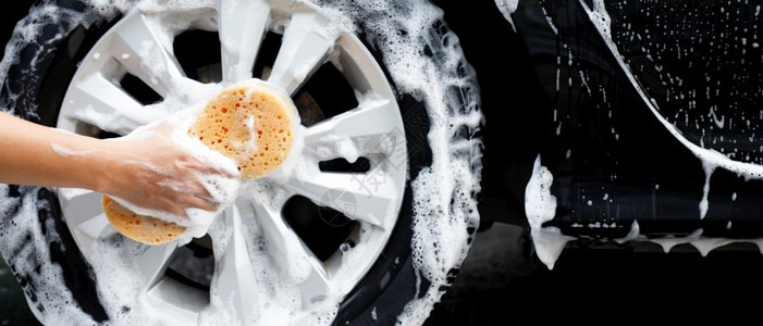 运输男子手持黄色海绵用于洗车清洁轮胎的洗库工人图片