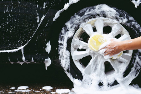 黄色的关心门男子手持黄色海绵用于洗车清洁轮胎的洗图片
