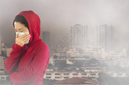 亚洲人妇女有流感喷嚏妇女穿着粉红色的冬季衣着戴面罩在她的鼻子上面对曼谷市覆盖有毒尘埃的感寒冷和流健康概念身穿针粉色的冬季衣服对曼设计图片