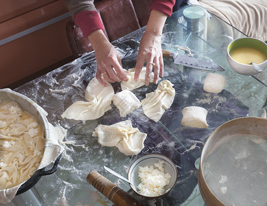一种面包店揉女人双手在玻璃桌上卷着面团做蛋糕干芝士面包馅饼加卷心菜图片