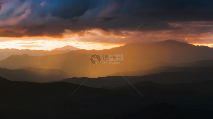 戏剧闪亮的日落时风景灿烂的山脉在幕后掩藏落日的暴雨神奇聚光灯通过乌云闪耀到山上以为焦点想像力图片