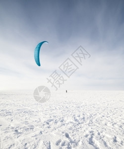 阳光速度Kite冲浪手被他的风筝拉扯穿过雪中滑板车在上放蓝风筝活动图片
