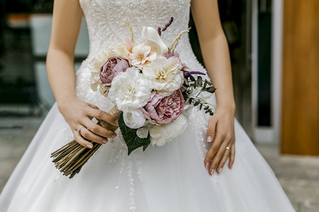 汗心白色的穿着裙子新娘手握着一束花朵丰富多彩的图片