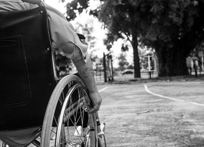 阳光车辆障碍在户外公共园黑白风格的调子中坐在轮椅上的残疾妇女身后放松图片