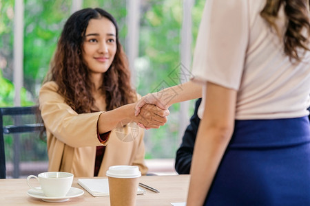 团体亚洲人在年轻妇女与两名在会议室有积极动的经理之间达成面谈协议后密切握手与经理企业雇用新会员概念经理握手并进行接触以及合伙背景图片